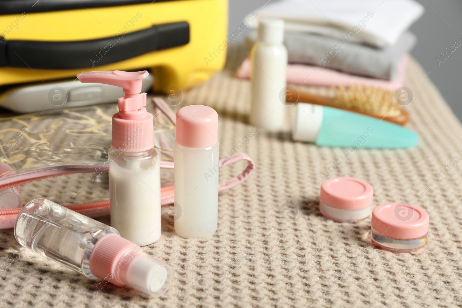 Photo of Cosmetic travel kit and plastic bag near suitcase on bed