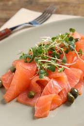 Photo of Delicious salmon carpaccio with capers and microgreens on plate, closeup