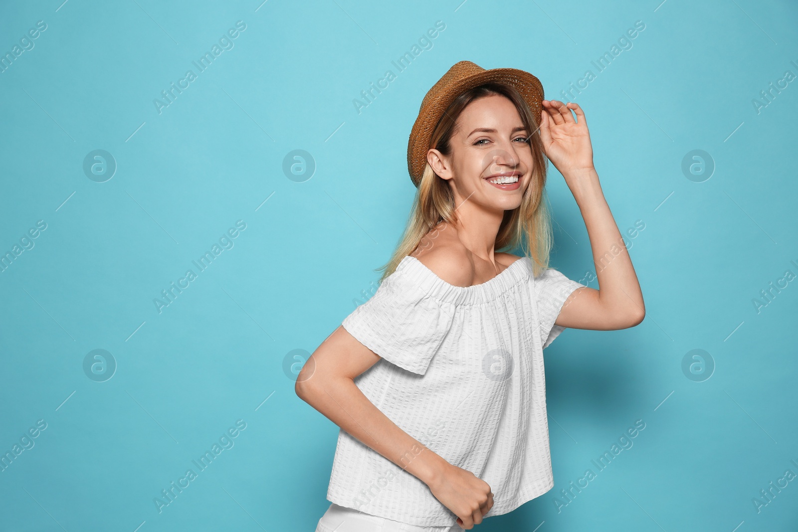 Photo of Beautiful young woman wearing straw hat on light blue background, space for text. Stylish headdress