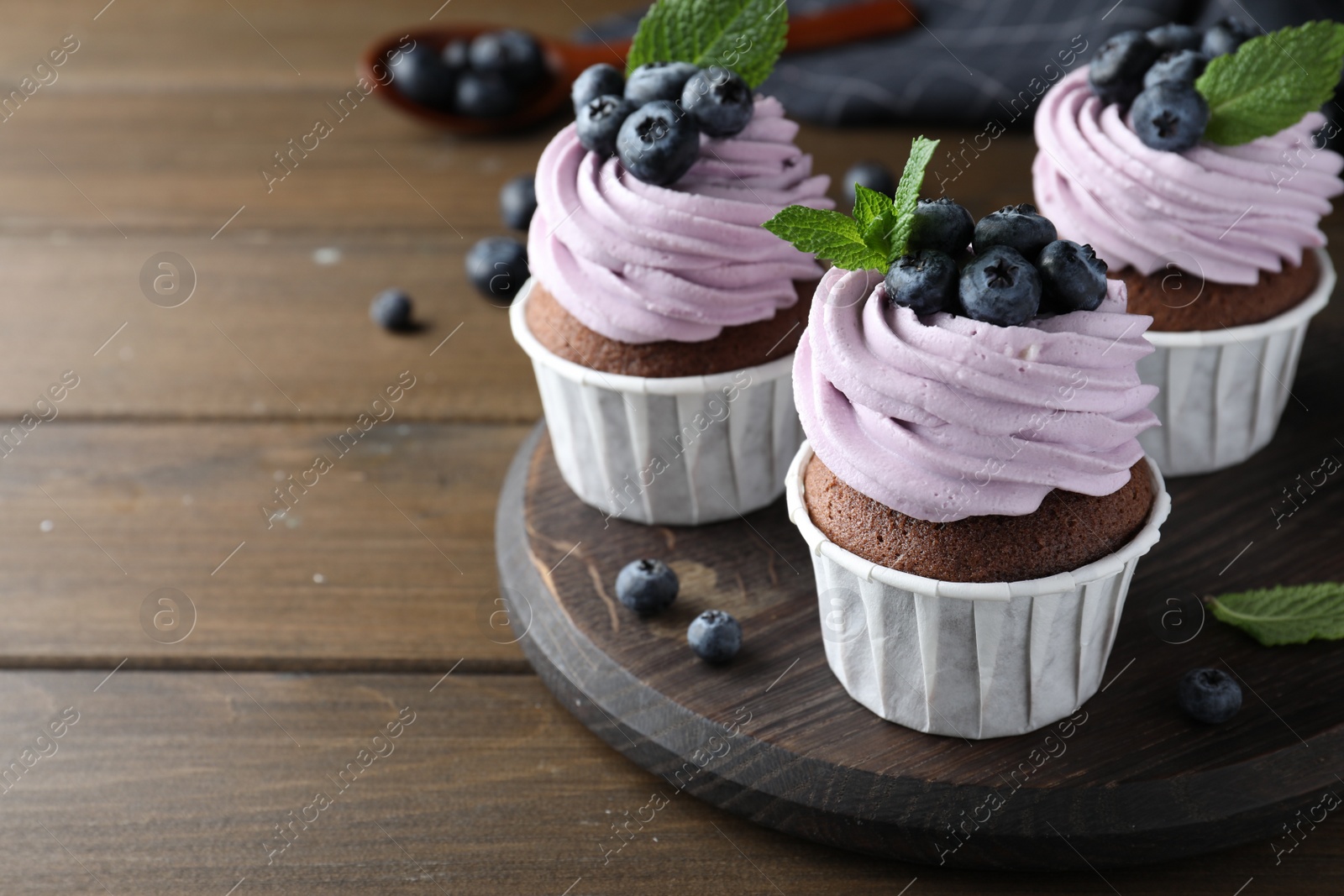 Photo of Sweet cupcakes with fresh blueberries on wooden table. Space for text