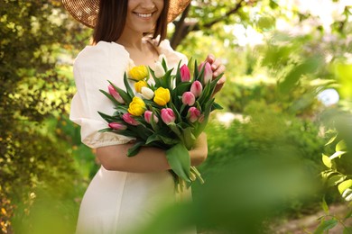 Photo of Young woman with bouquet of tulips in park on sunny day, closeup