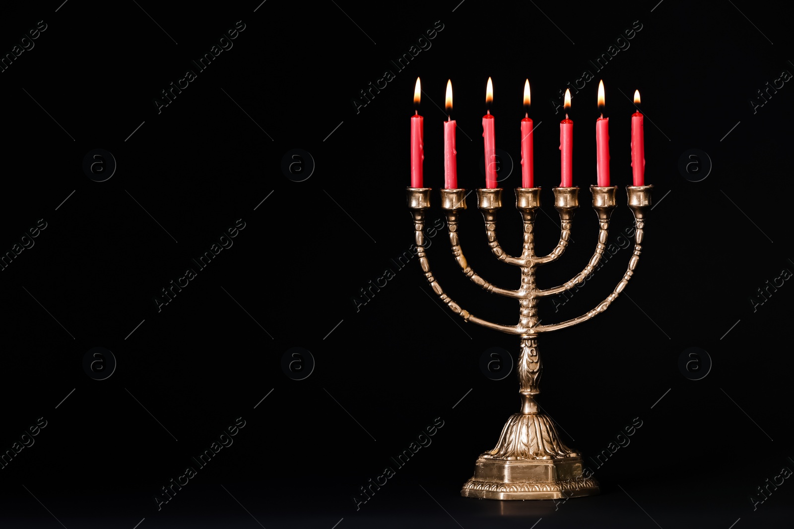 Photo of Golden menorah with burning candles on black background, space for text