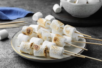 Photo of Sticks with roasted marshmallows on grey table