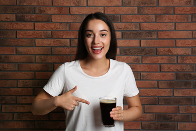 Photo of Beautiful woman with cold kvass near brick wall. Traditional Russian summer drink