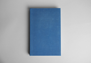 Photo of Hardcover book on light grey background, top view. Space for design