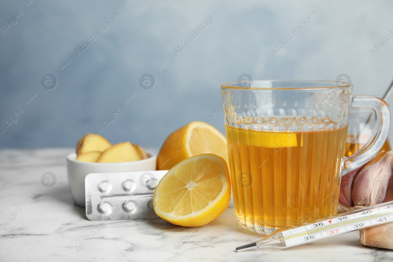 Photo of Composition with cold remedies on marble table against blue background. Sore throat treatment