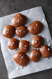 Photo of Tasty caramel candies and salt on grey table, top view