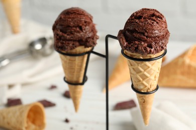 Photo of Chocolate ice cream scoops in wafer cones on stand, closeup