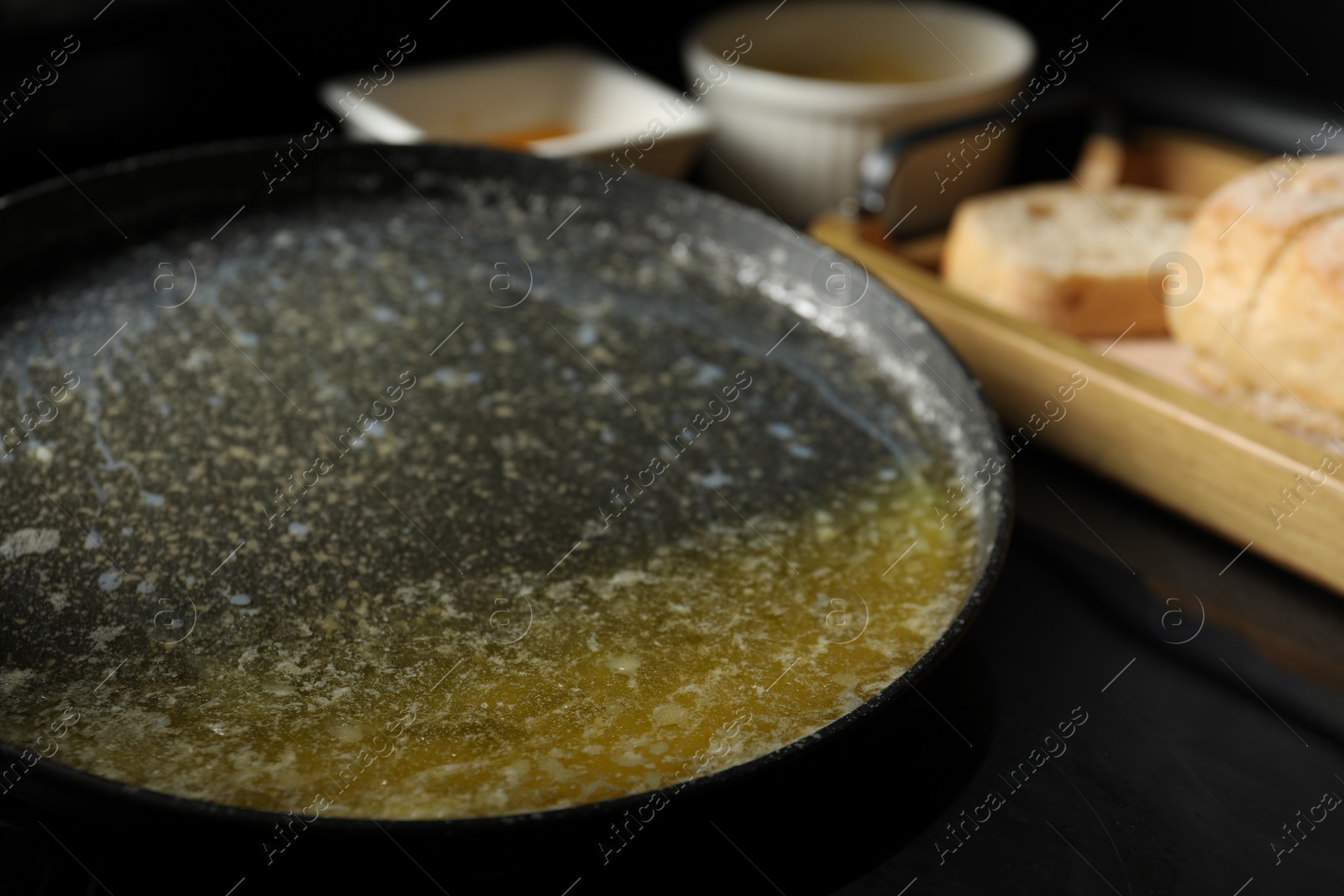 Photo of Melted butter in frying pan on black table, closeup