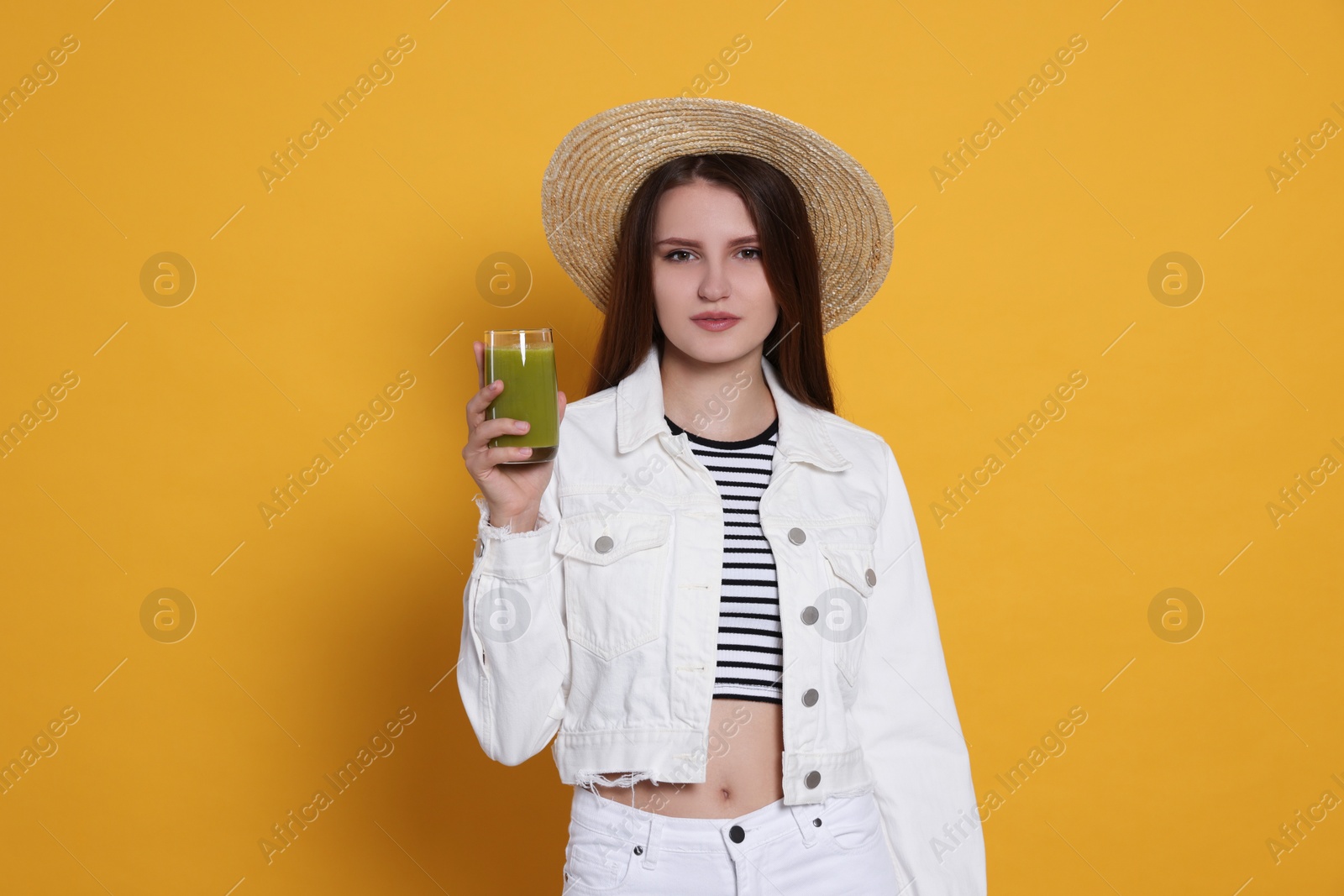 Photo of Beautiful young woman with glass of juice on yellow background