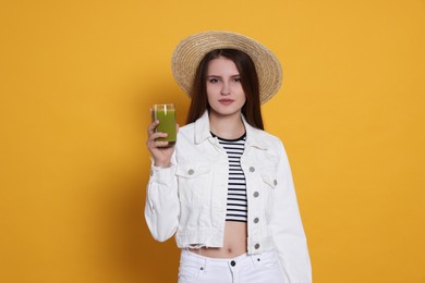 Photo of Beautiful young woman with glass of juice on yellow background