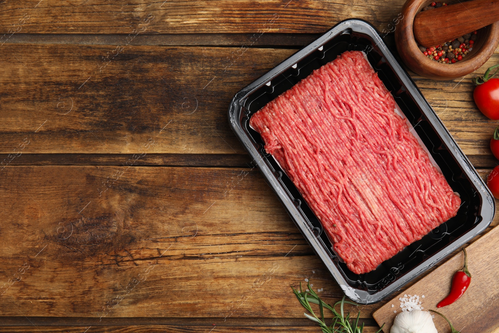 Photo of Raw fresh minced meat and other ingredients on wooden table, flat lay. Space for text