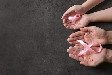 Photo of Woman and girl holding pink ribbons on grey background, top view with space for text. Breast cancer awareness