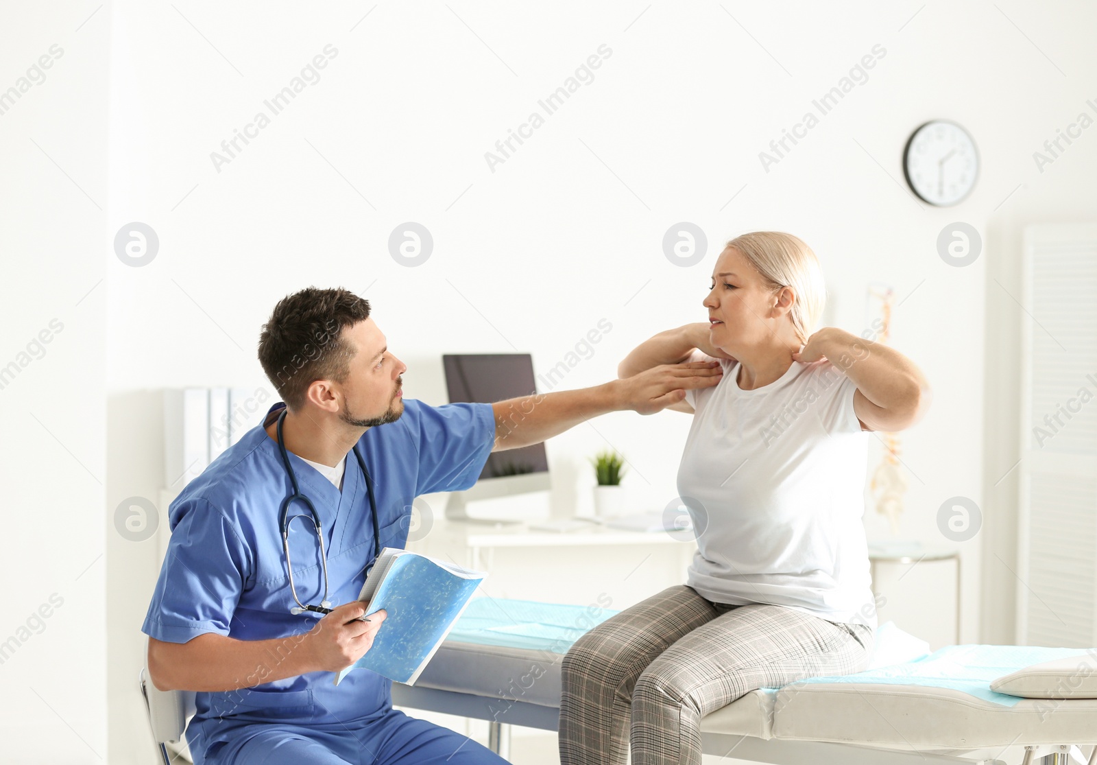 Photo of Male orthopedist examining patient with injured neck in clinic