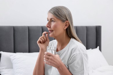 Beautiful woman taking vitamin pill in bedroom