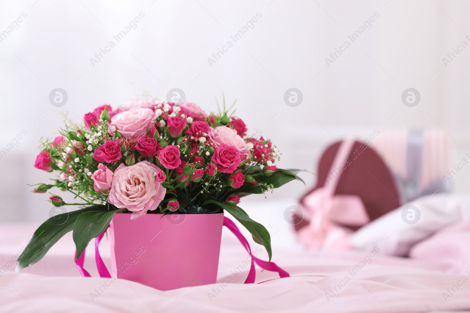 Photo of Beautiful bouquet of flowers in paper gift box on bed. Space for text