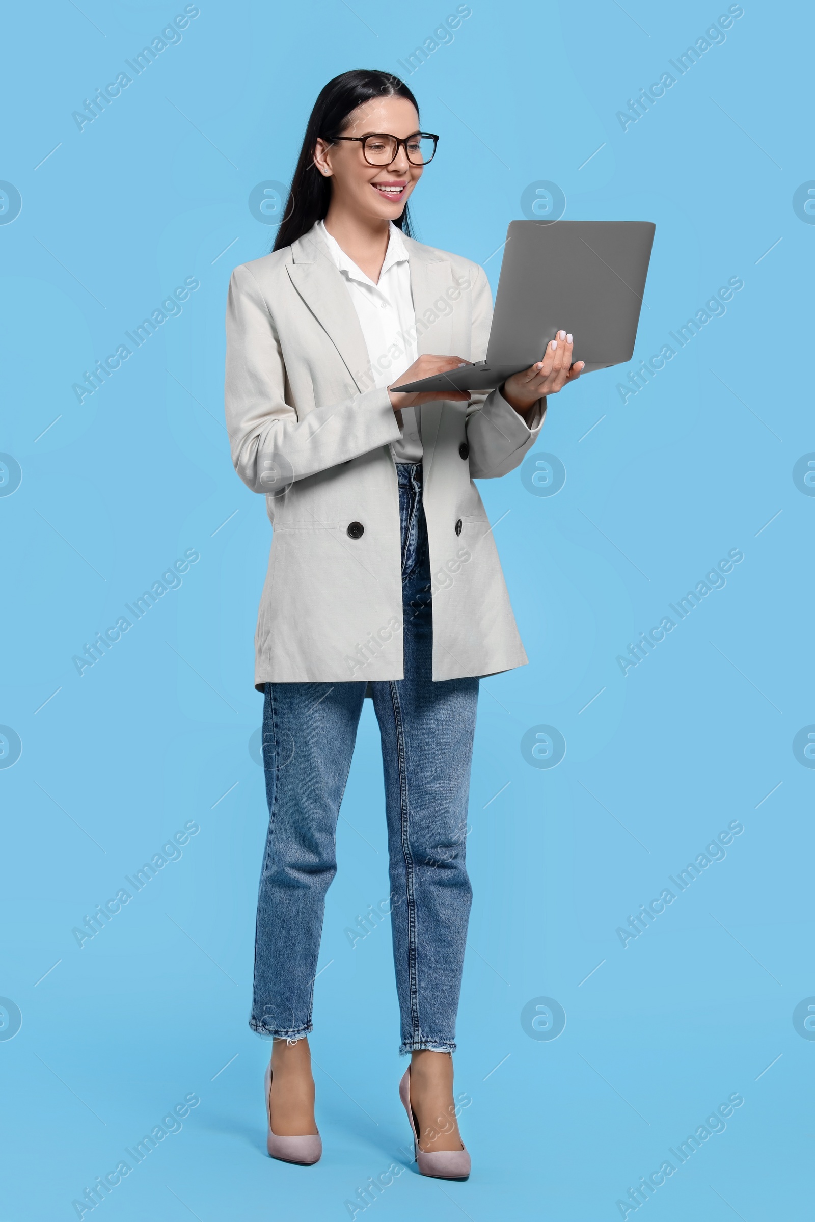 Photo of Happy woman using laptop on light blue background