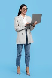 Happy woman using laptop on light blue background