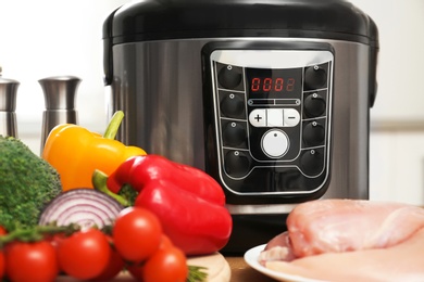 Modern multi cooker and ingredients on wooden table