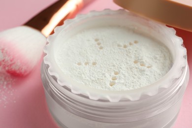 Photo of Rice loose face powder and makeup brush on pink background, closeup