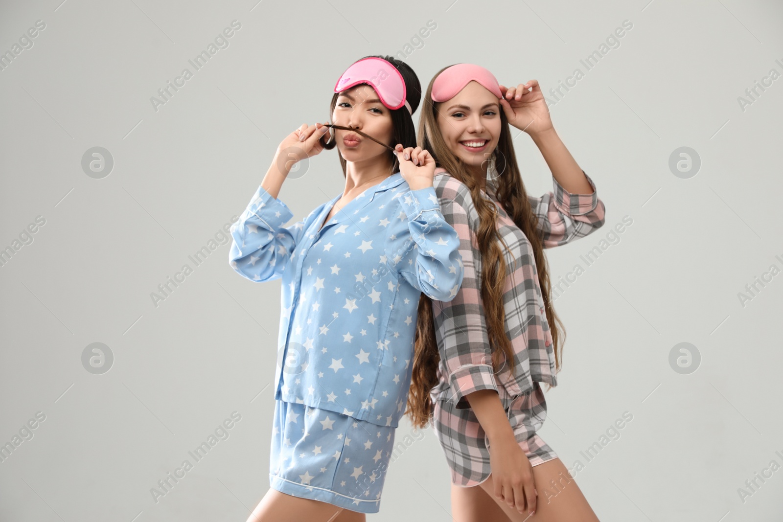 Photo of Beautiful women in pajamas on light grey background. Bedtime