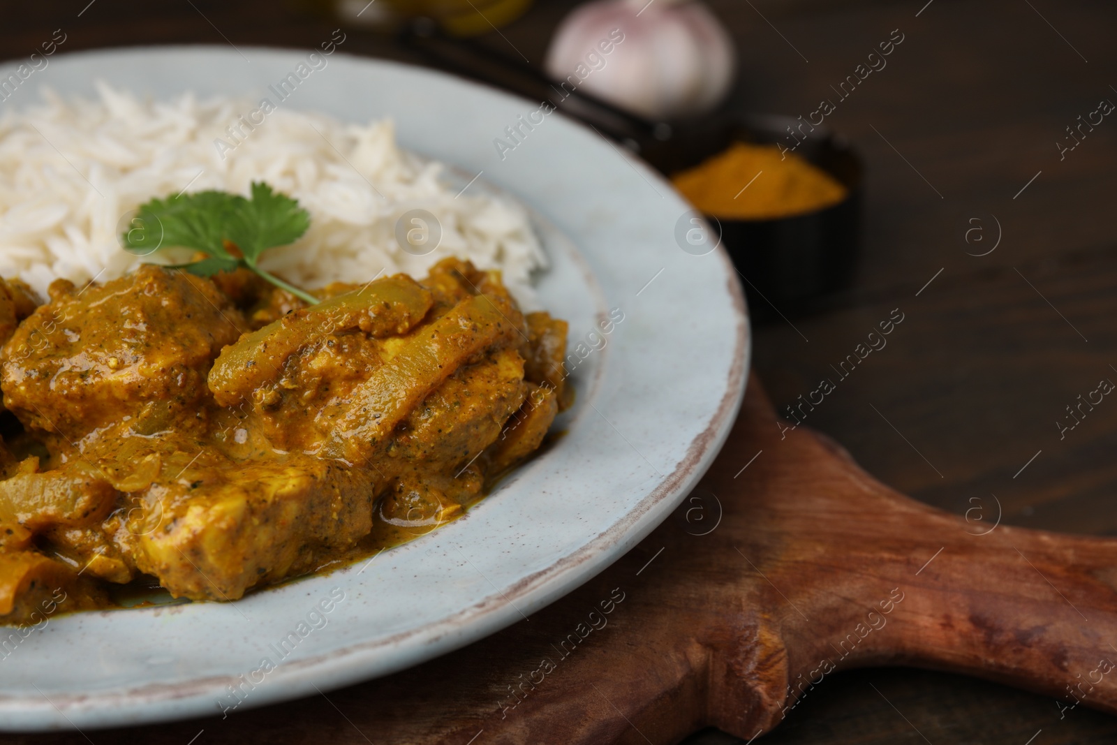 Photo of Delicious chicken curry with rice on wooden table, closeup