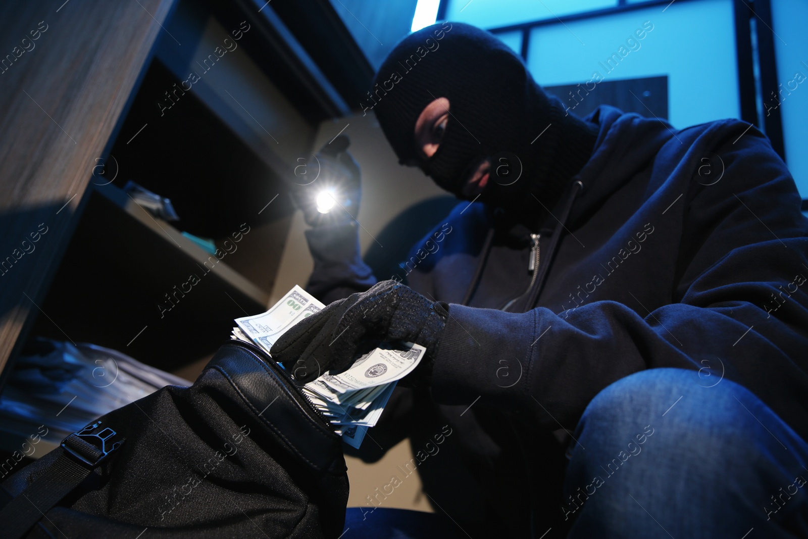 Photo of Thief taking money out of steel safe indoors at night