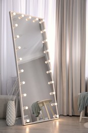 Photo of Large mirror with light bulbs near window in room. Interior design