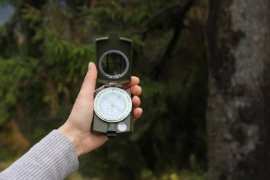 Photo of Woman using compass during hiking in forest, closeup