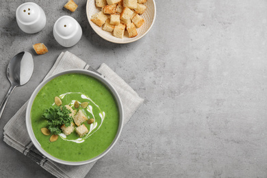 Photo of Tasty kale soup with croutons served on grey table, flat lay. Space for text