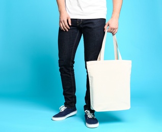 Photo of Young man with eco bag on blue background, closeup