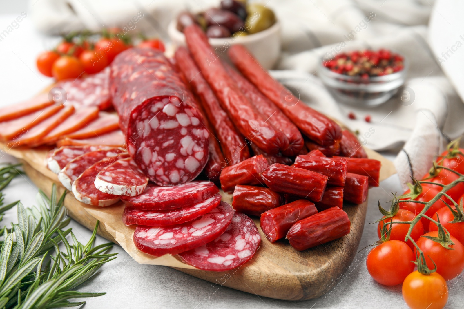 Photo of Different types of delicious sausages and ingredients on light grey table, closeup