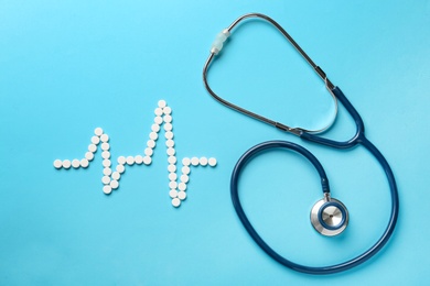 Photo of Flat lay composition with stethoscope and pills on light blue background