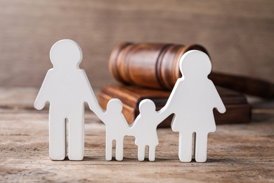 Photo of Figure in shape of people and gavel on wooden table. Family law concept