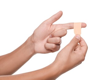 Photo of Man putting sticking plaster onto finger on white background, closeup