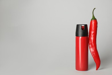 Bottle of gas spray and fresh chili pepper on light grey background. Space for text