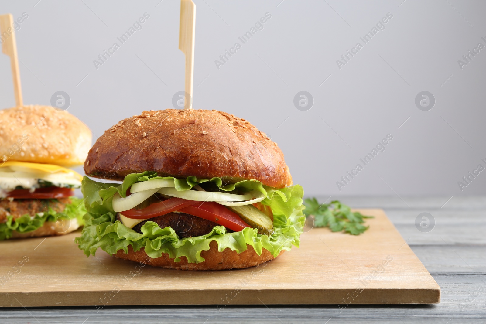 Photo of Delicious vegetarian burgers served on grey wooden table