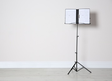 Photo of Note stand with music sheets near white wall indoors. Space for text