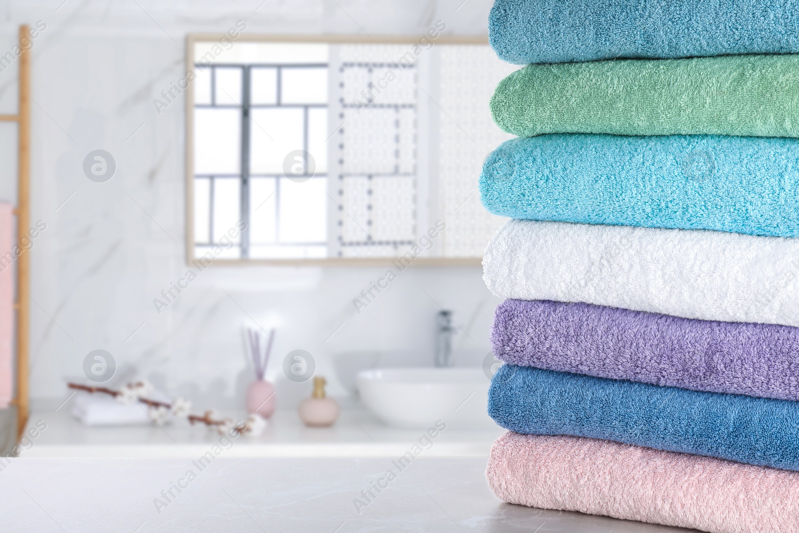 Image of Stack of fresh towels on light grey table in bathroom. Space for text