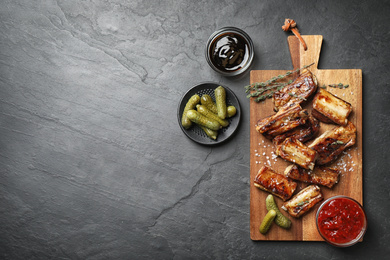 Delicious grilled ribs served on black table, flat lay. Space for text