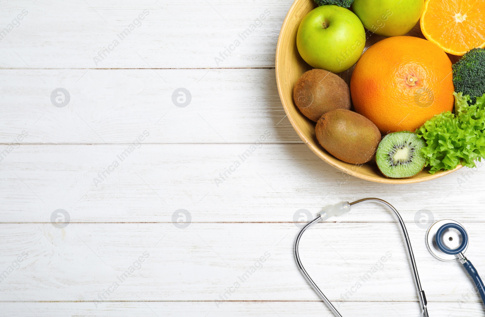 Photo of Fruits, vegetables and stethoscope on white wooden background, flat lay with space for text. Visiting nutritionist