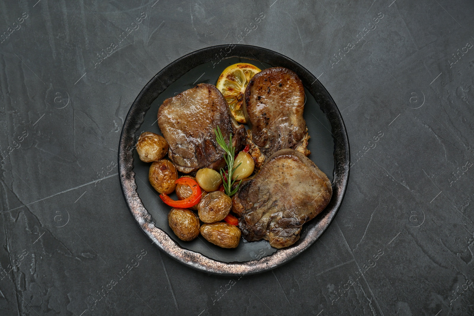 Photo of Tasty beef tongue pieces, rosemary, lemon and potatoes on grey table, top view