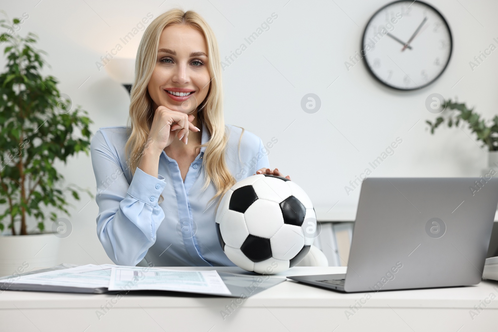 Photo of Happy woman with soccer ball at table in office