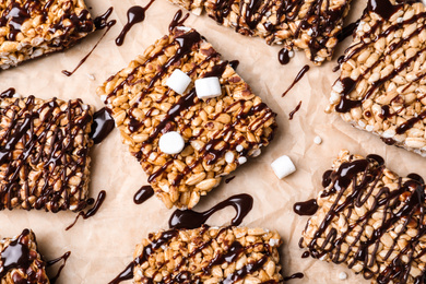 Photo of Delicious rice crispy treats on parchment paper, flat lay