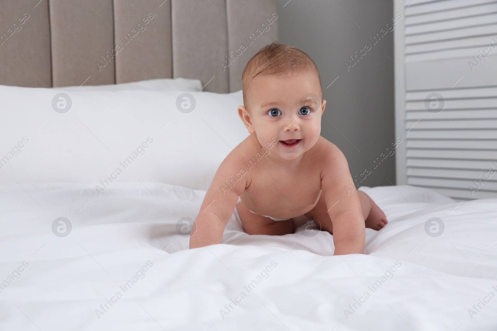 Photo of Cute baby in dry soft diaper on white bed at home