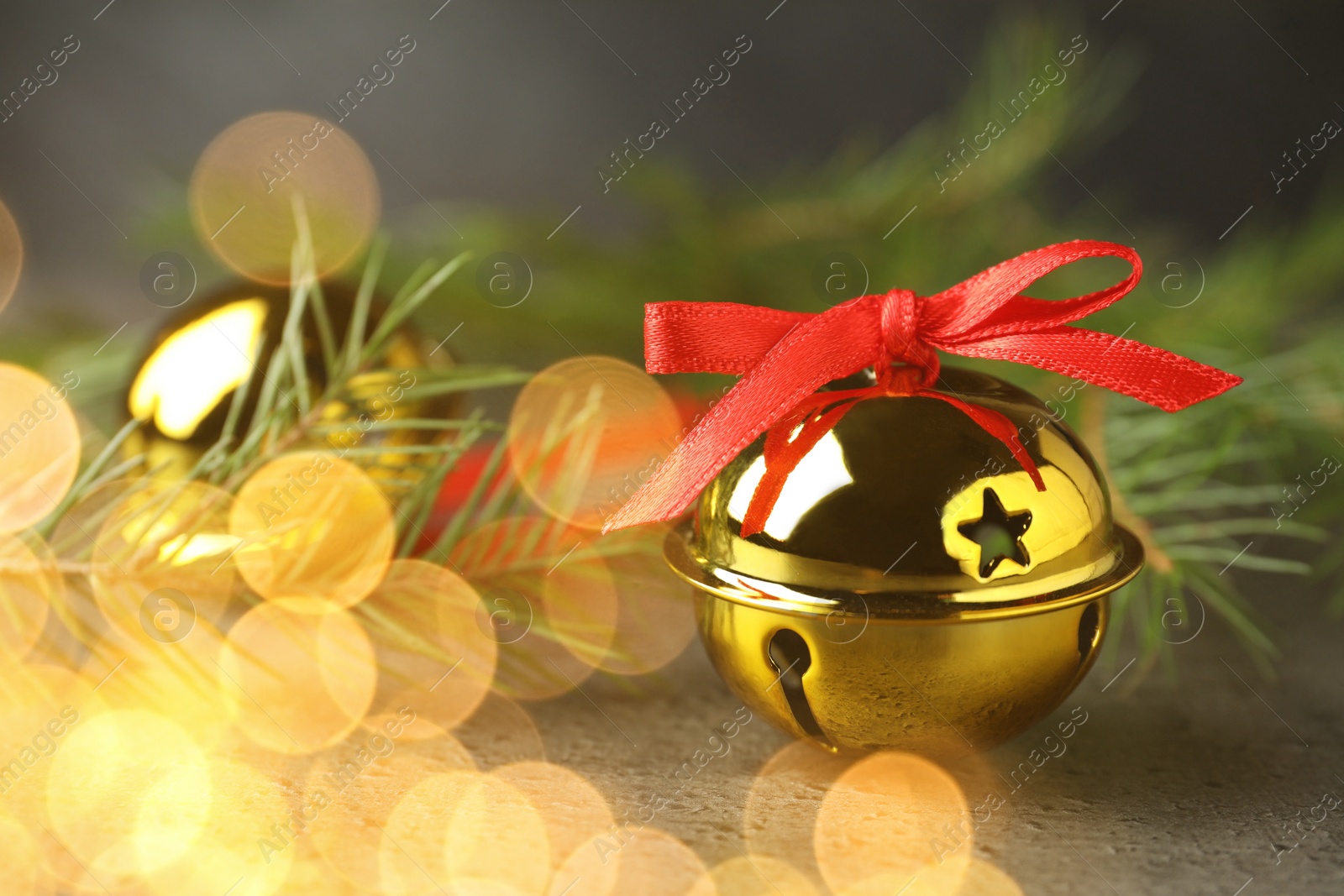 Image of Christmas music. Jingle bells and fir tree branch on grey table, bokeh effect