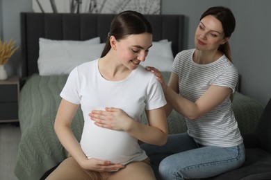 Doula taking care of pregnant woman in bedroom. Preparation for child birth