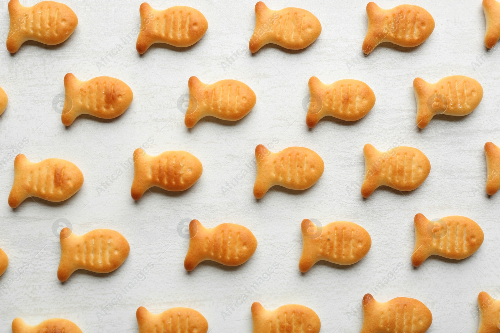 Photo of Delicious goldfish crackers on white table, flat lay