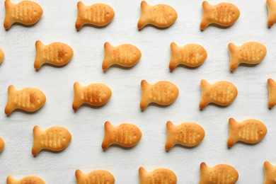 Photo of Delicious goldfish crackers on white table, flat lay