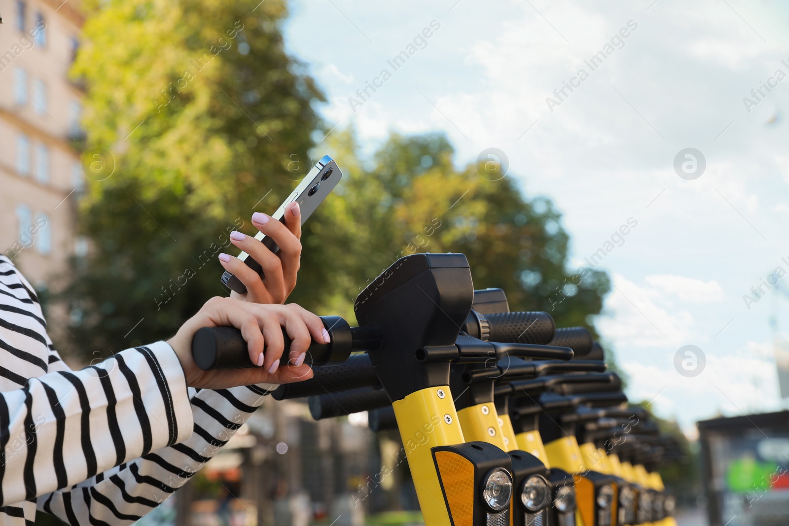 Photo of Woman using smartphone to pay and unblock electric kick scooter outdoors, closeup